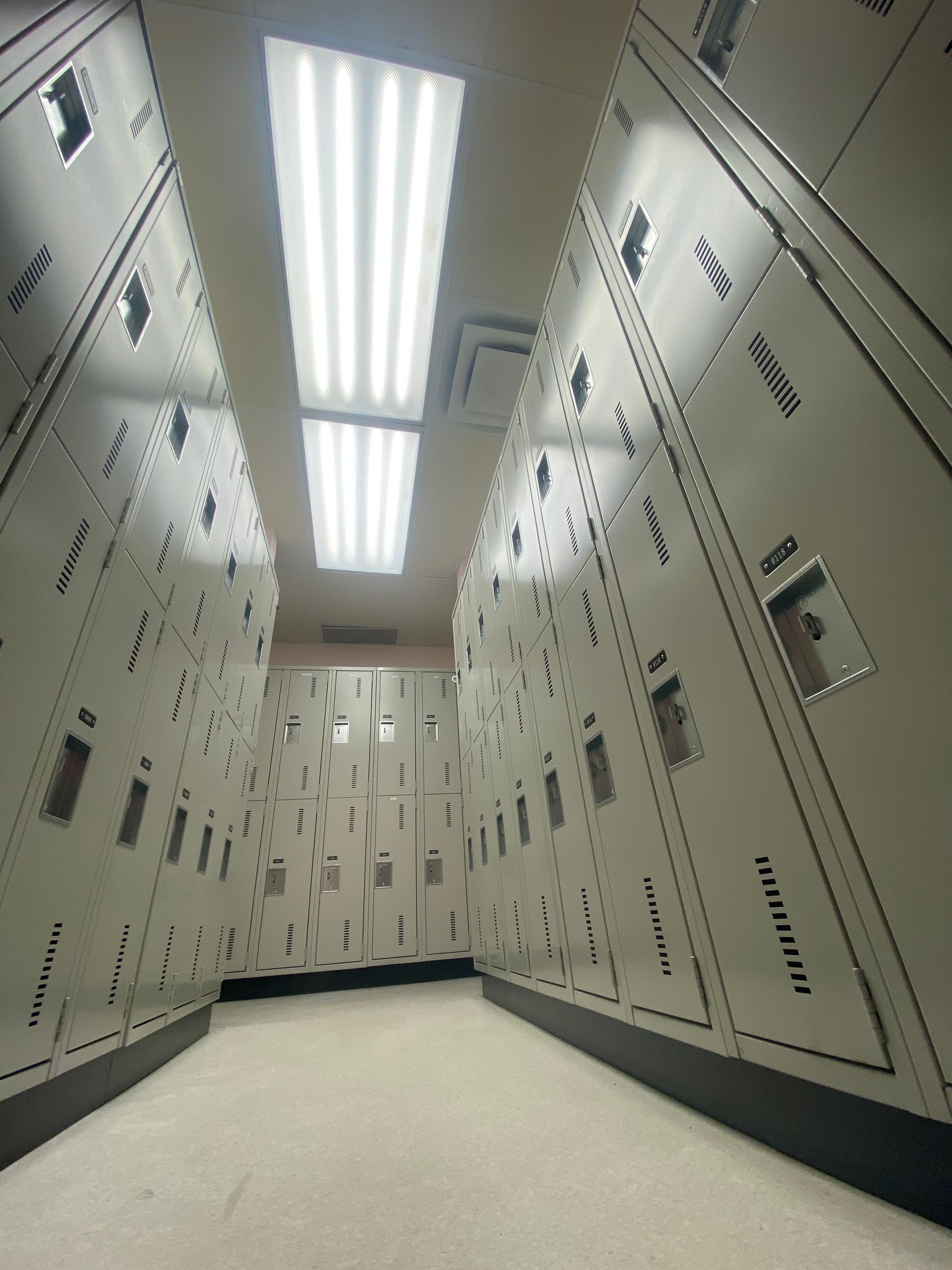 A very long hallway of lockers with a light on the ceiling