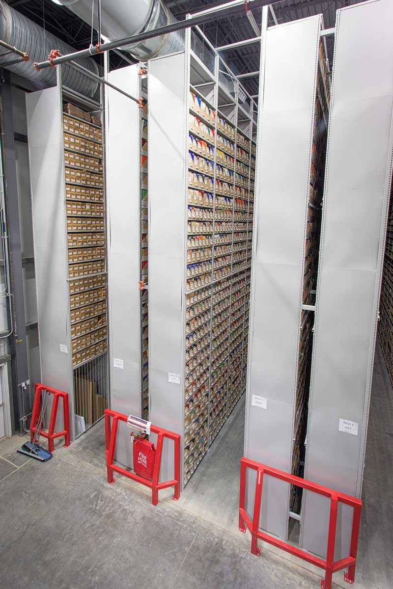 A warehouse filled with lots of shelves and red barriers.