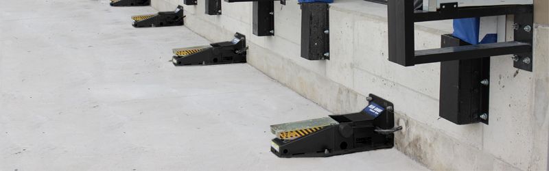 A row of black rubber pads attached to a concrete wall.