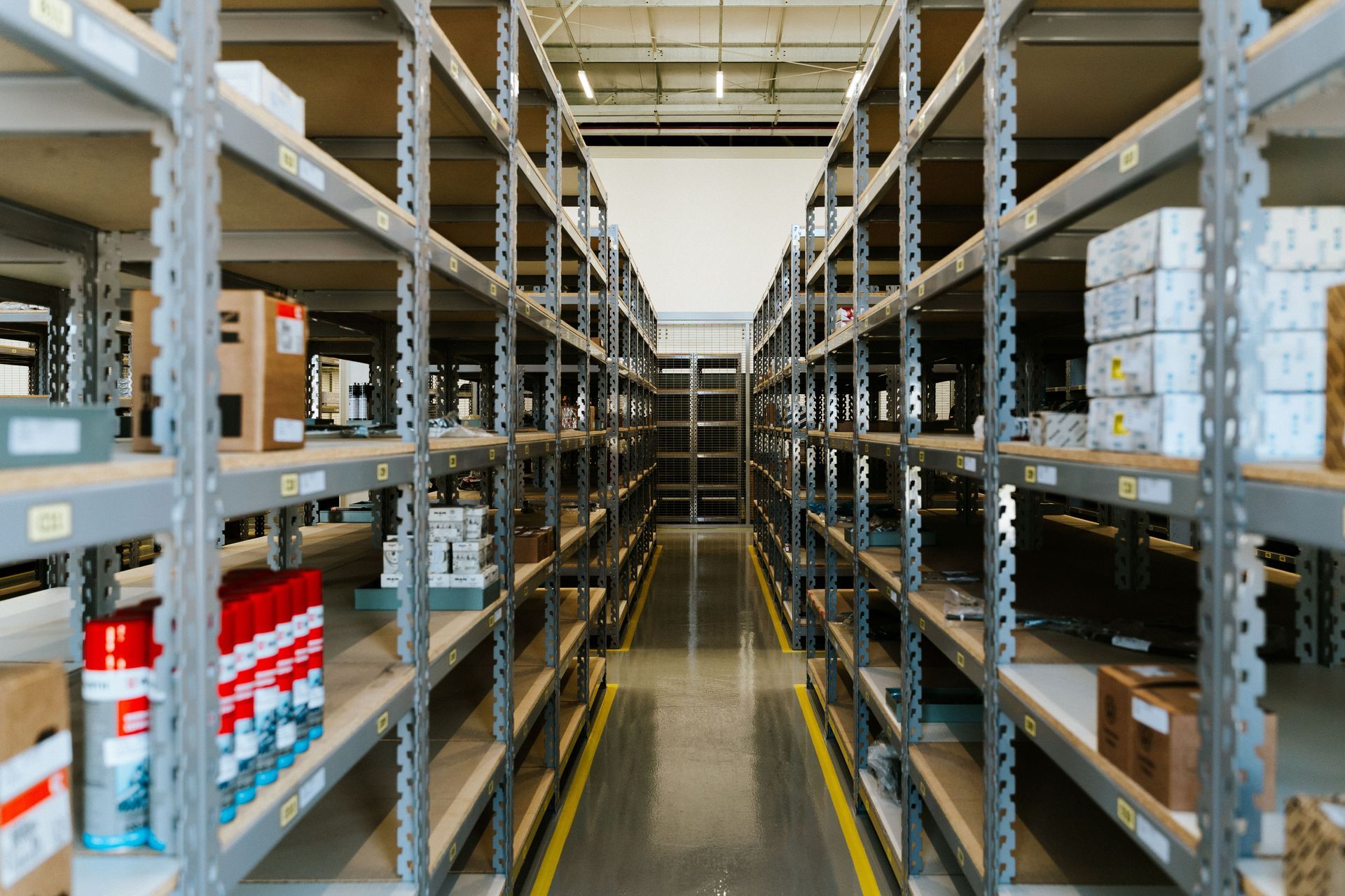 Warehouse aisle with tall metal shelves stocked with boxes and supplies on both sides