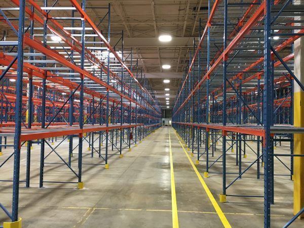 An empty warehouse with red and blue shelves and a yellow line on the floor