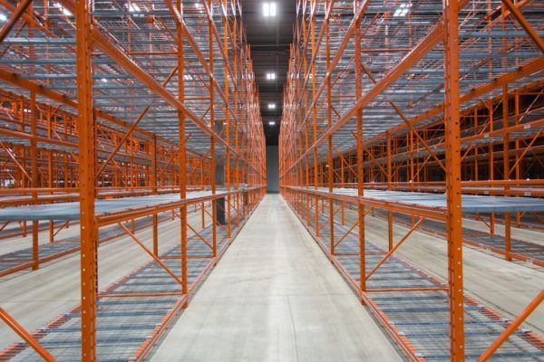An empty warehouse with orange shelves and a concrete floor.