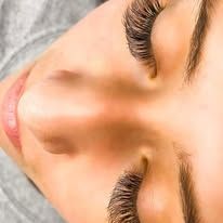 Close-up of eyes with long, dark, fluttery eyelash extensions, viewed from above.