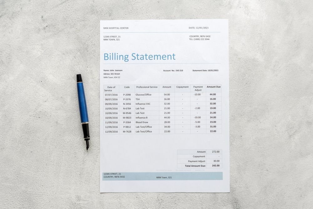 A billing statement paper lies on a gray textured surface next to a blue and silver fountain pen.