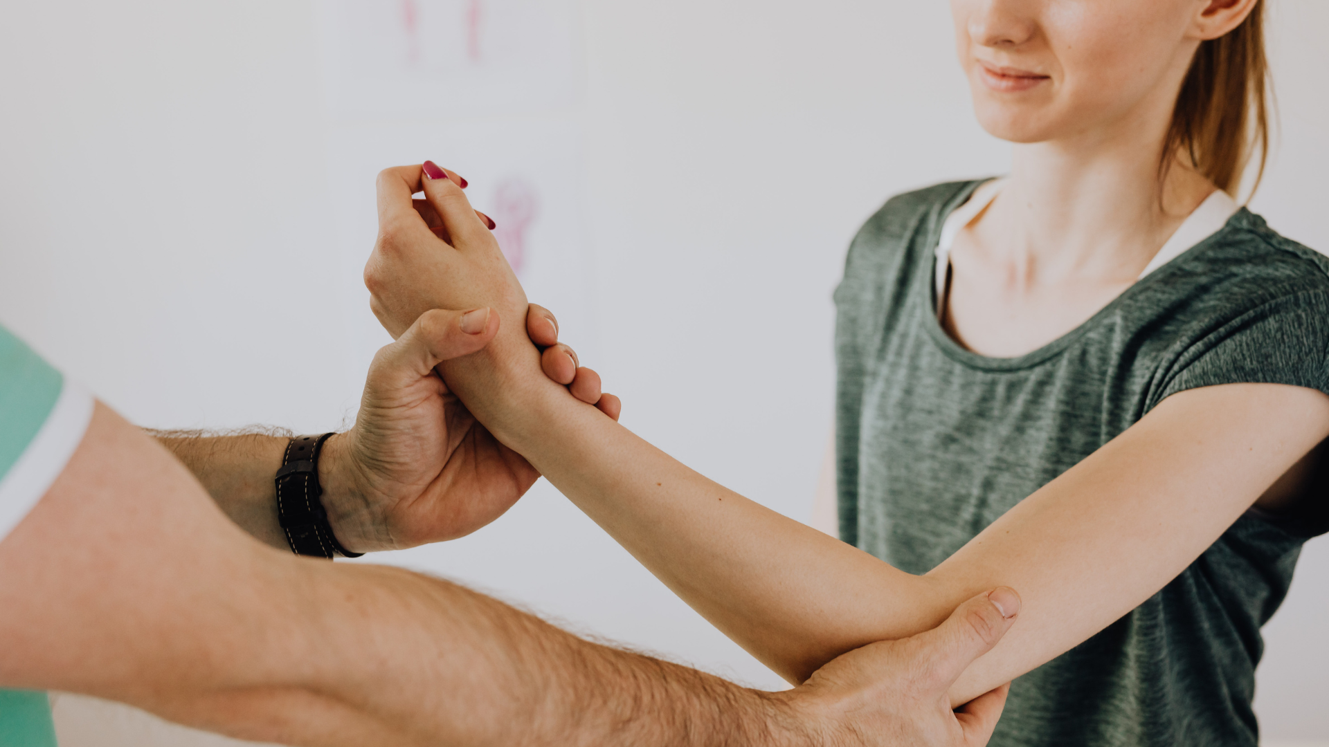Adult and child holding hands during a wrist stretch with a therapist assisting indoors