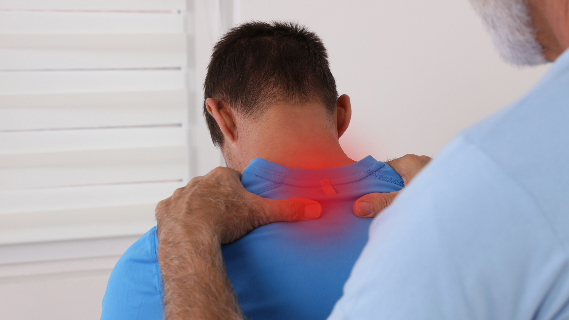 Person holding neck with red pain highlight while another person examines the shoulder area
