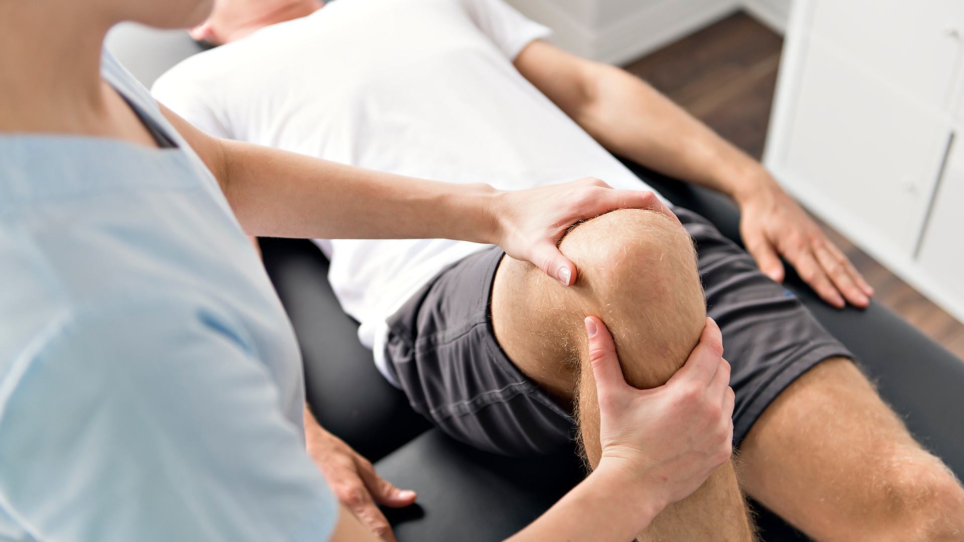 Physical therapist examining a patient’s knee during a clinic appointment