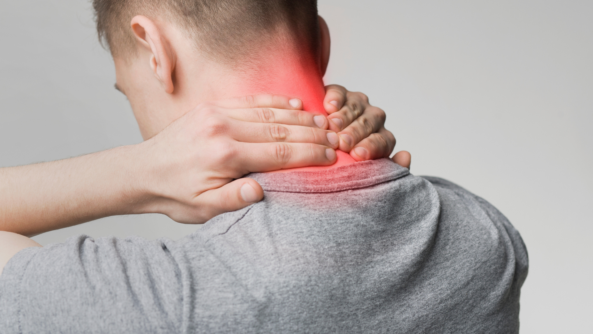 Person holding neck with red highlighted pain area on a gray background