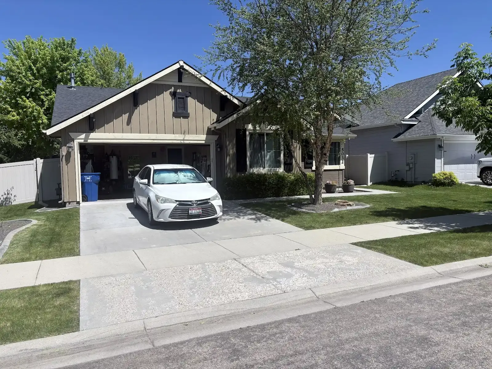 Suburban house with a car parked in the driveway and a tree in the front yard
