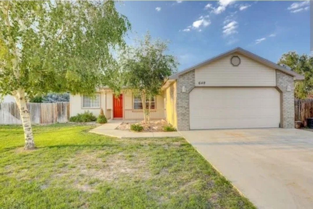 Suburban house with a two-car garage, red front door, and a front yard with trees
