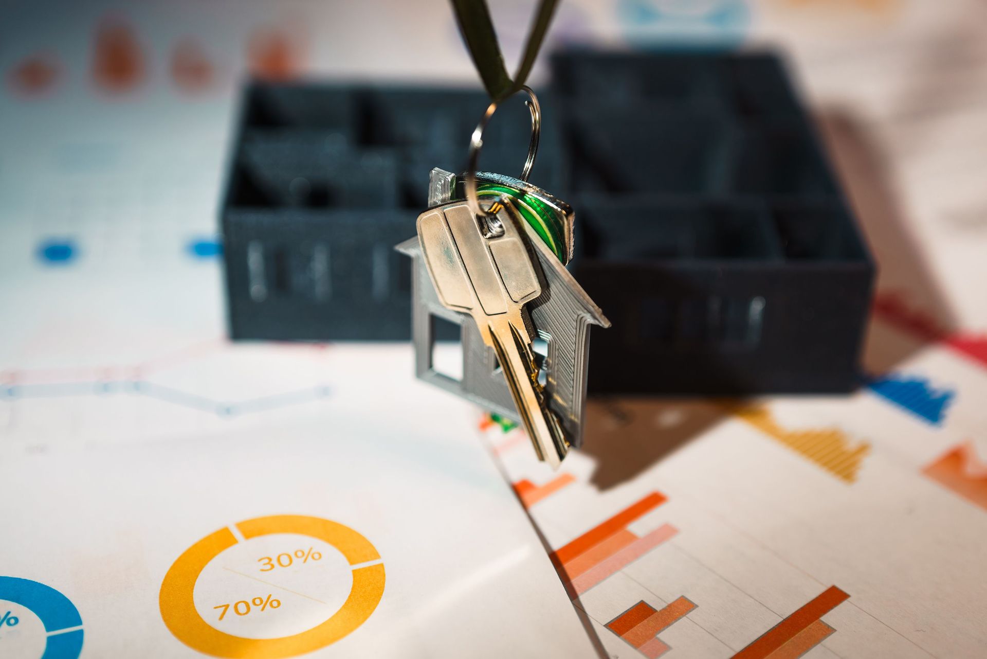 Keys on a lanyard over printed charts and graphs on a desk.