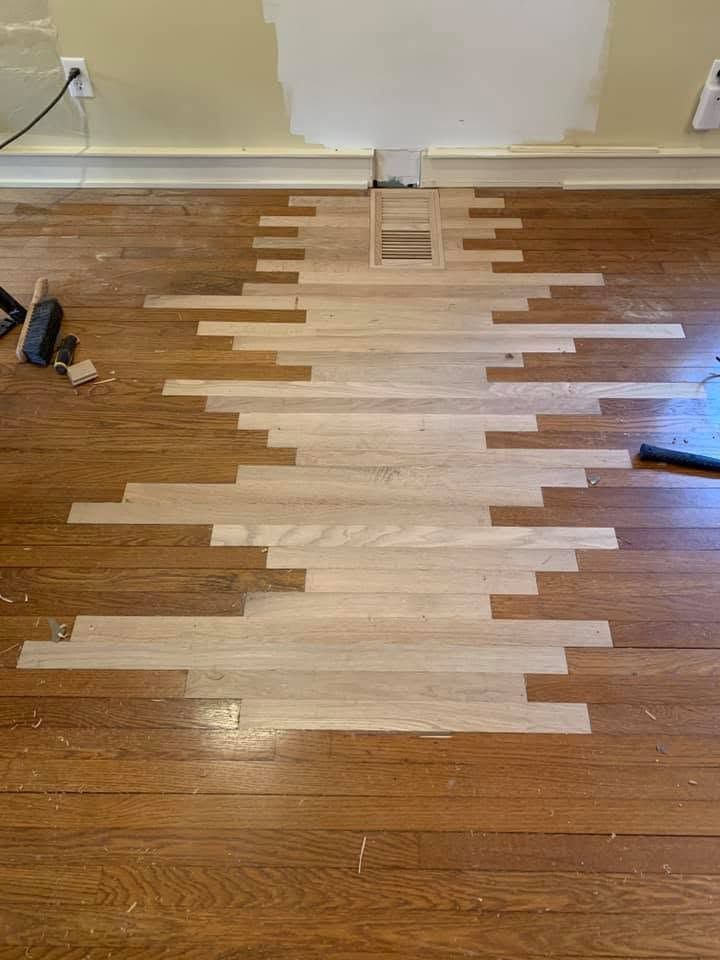 Floor with a damaged wood section covered by a patchwork repair of light-colored planks