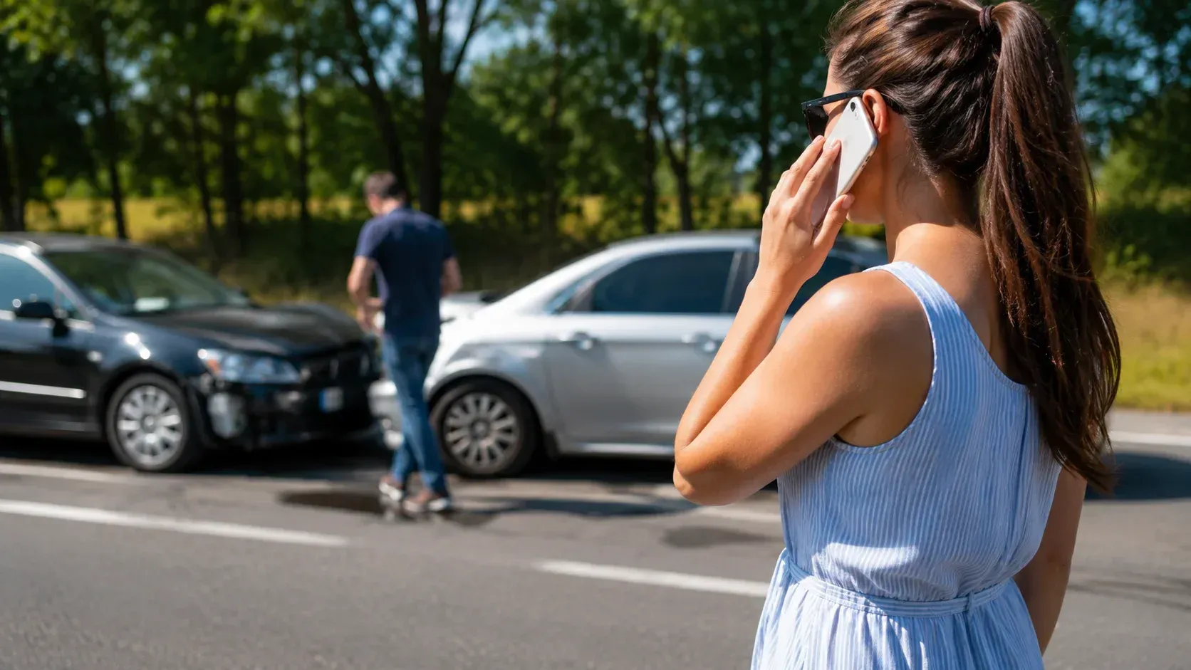 A woman stands next to a multi-vehicle collision on a sunny day, illustrating what to do after a car accident.