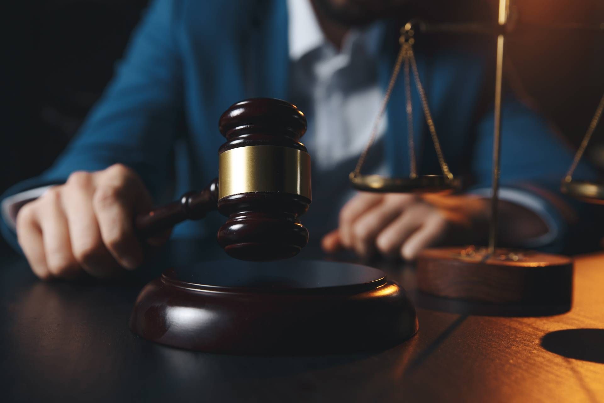 Judge holding gavel, with scales of justice in the background.