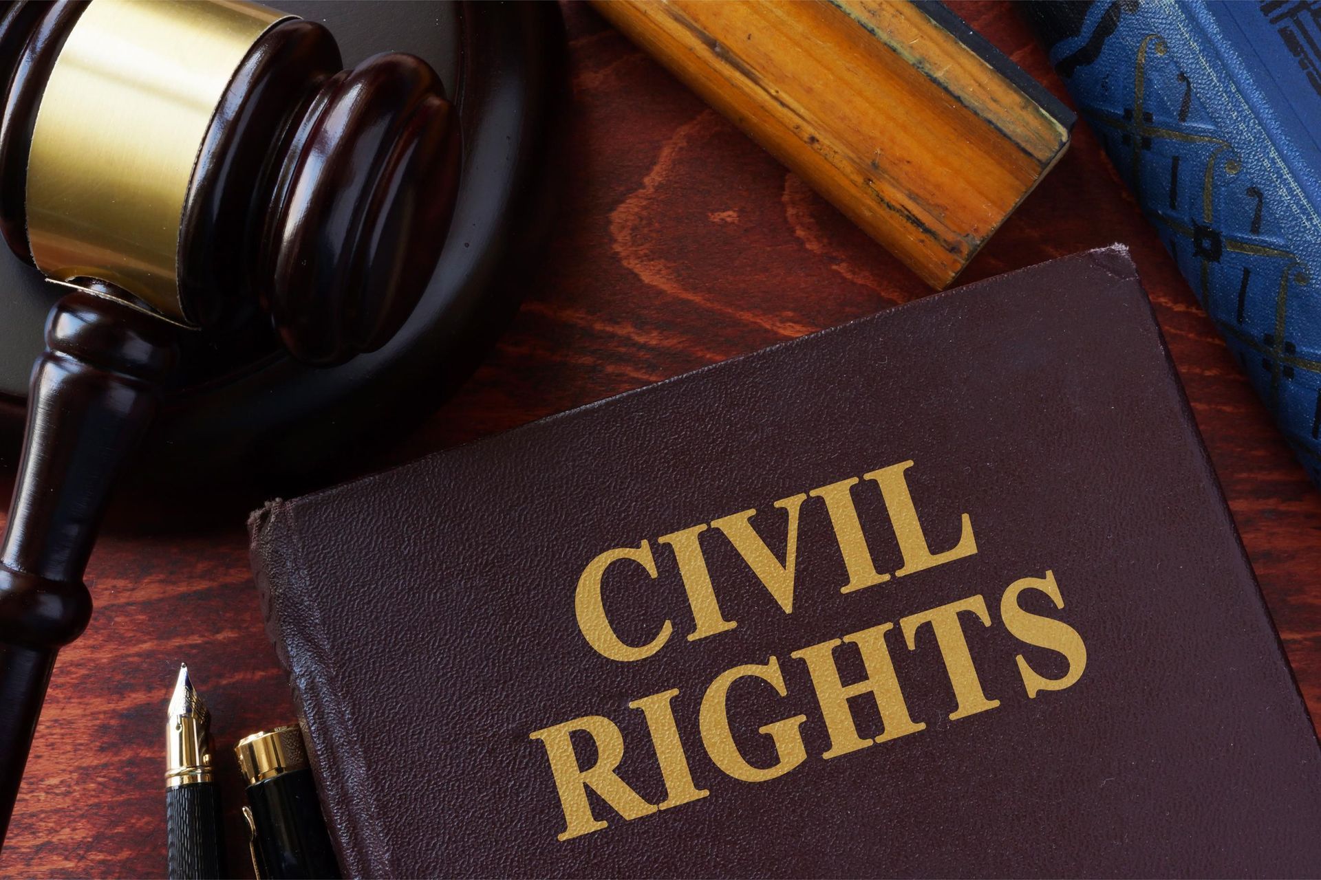 A judge’s gavel, a pen, and a book titled