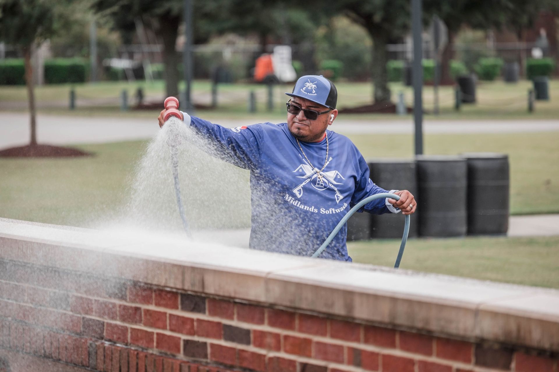 A man is spraying water on a brick wall with a hose.