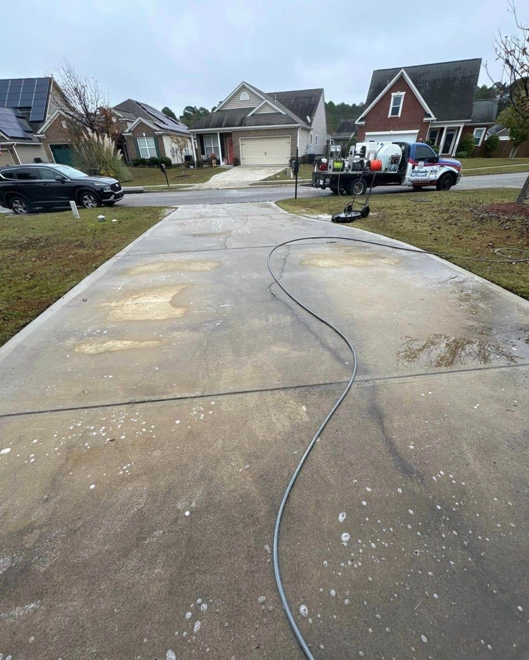 A concrete driveway is being cleaned in a residential neighborhood.