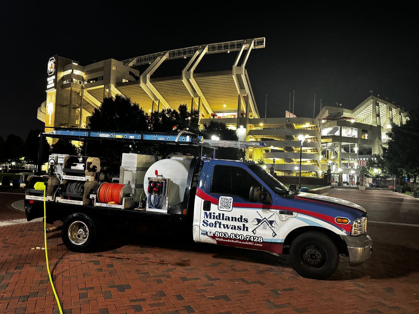 Tow truck with “Sunland” branding parked at night in front of a lit stadium or arena