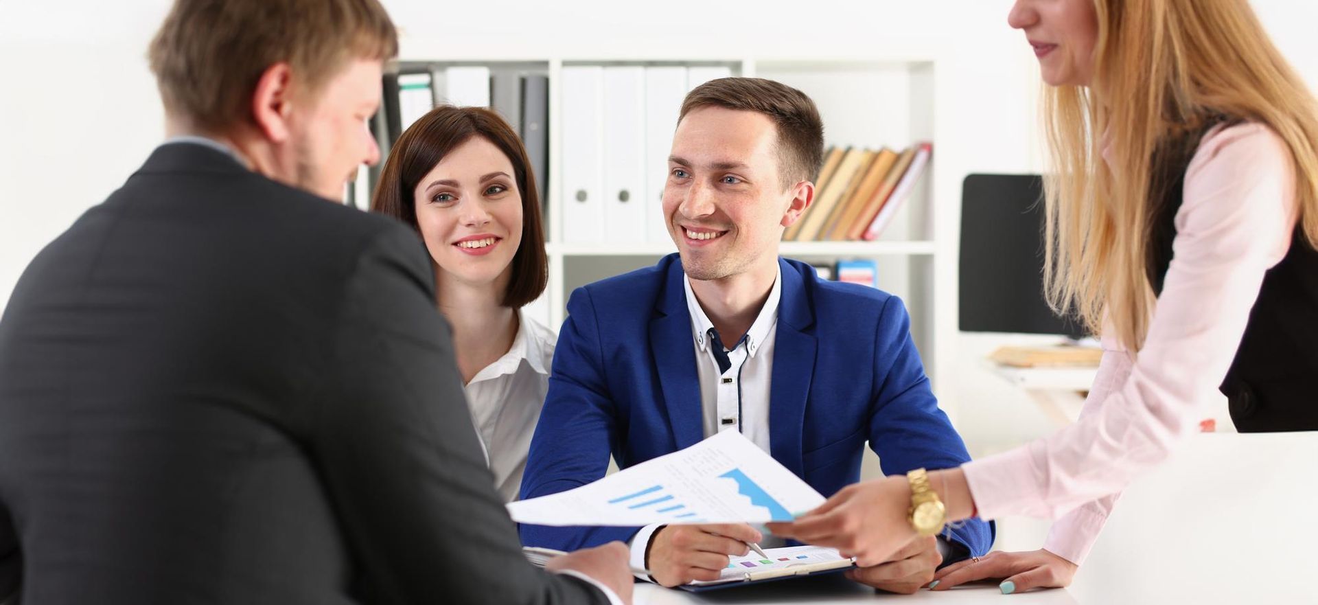 Business meeting with four people smiling around a table in a bright office