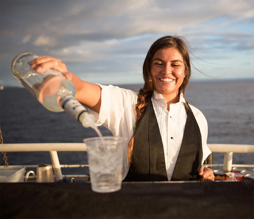 A woman is pouring a drink from a bottle into a glass
