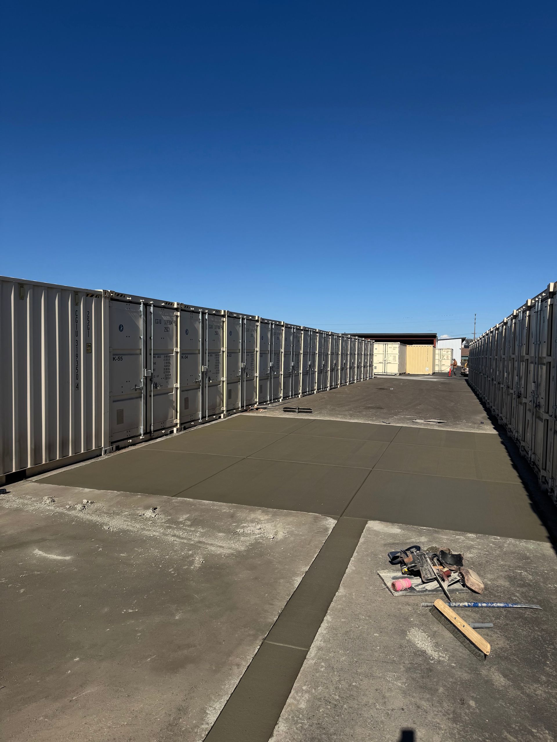 Empty rooftop with metal railings, blue sky, and scattered debris on the ground.