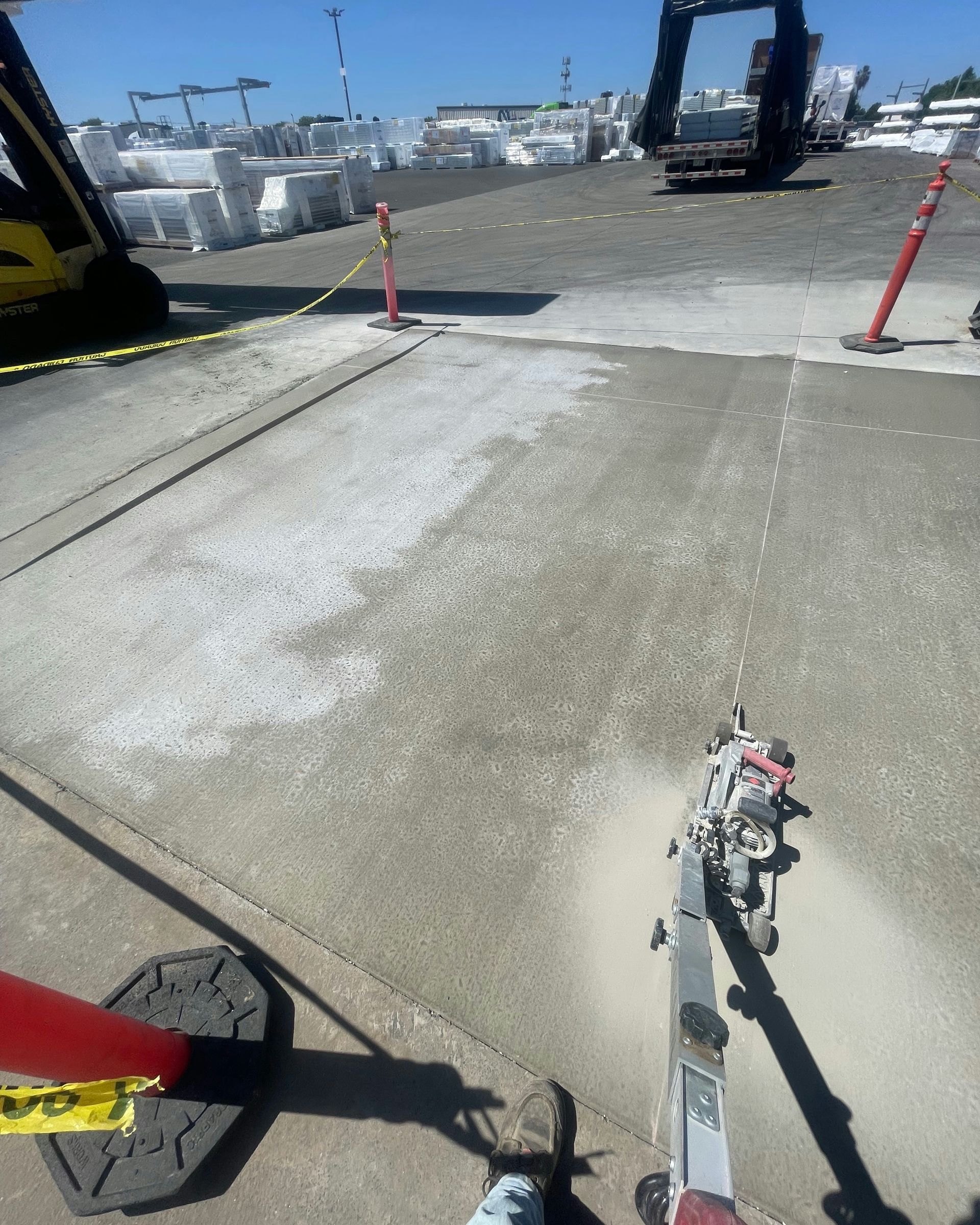 Concrete work zone with cones and a construction machine on a sunny industrial lot