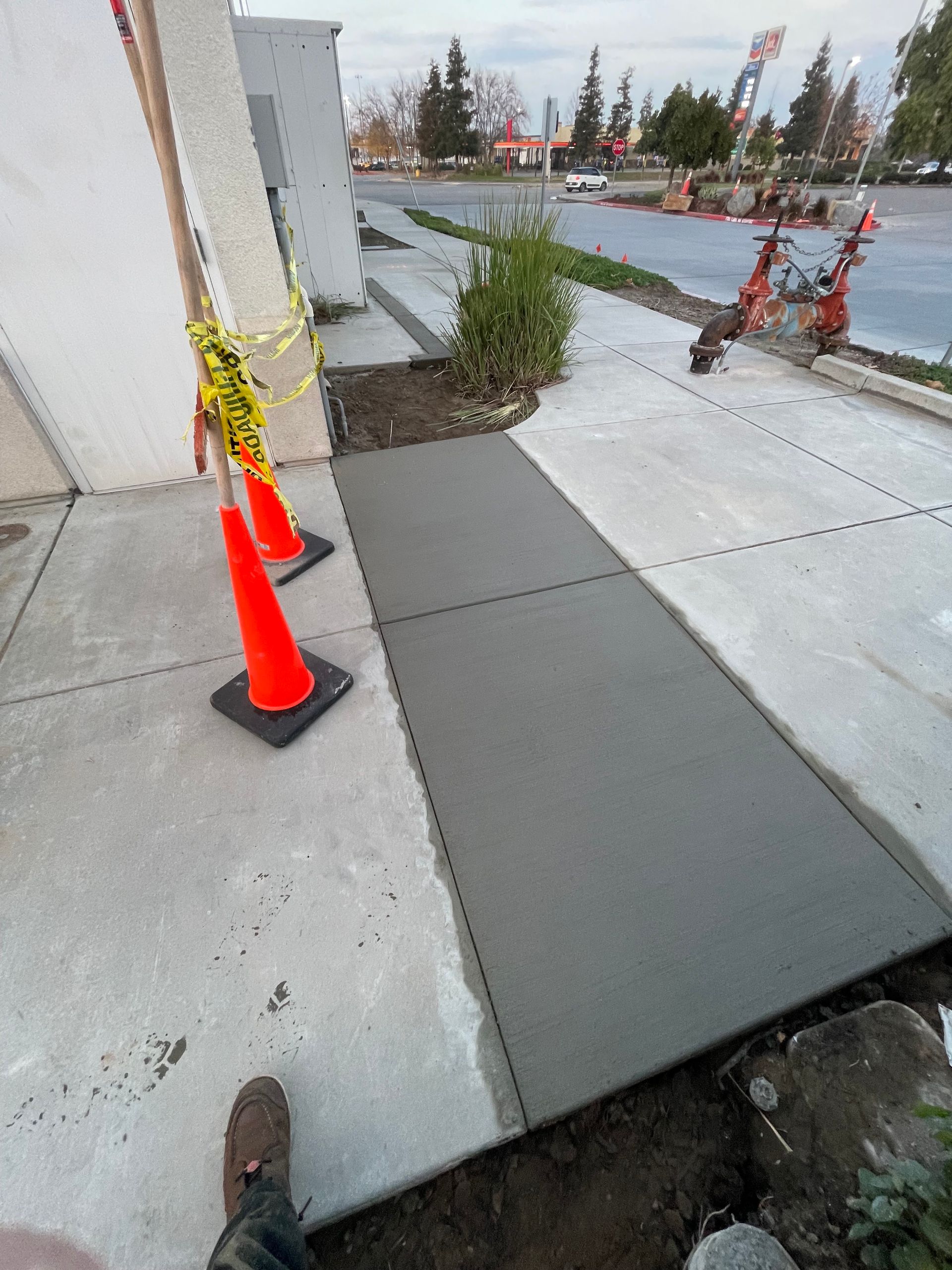Caution cones beside a temporary plywood sidewalk ramp on a wet street corner