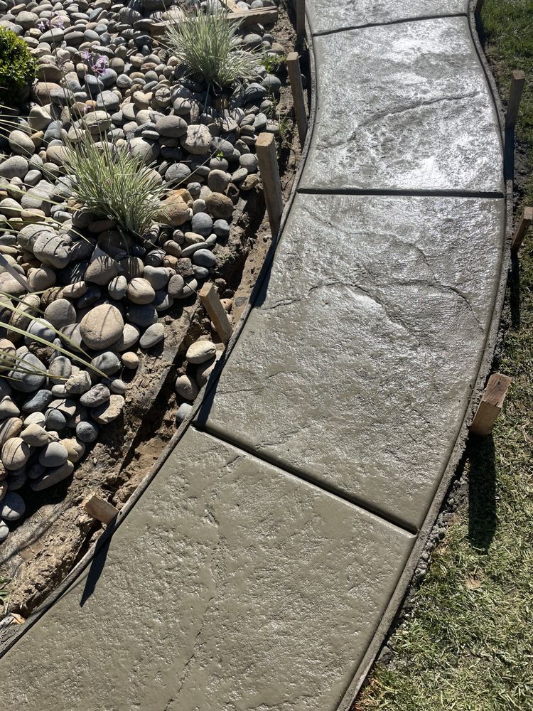 Curved concrete garden path beside a rock and succulent landscape bed