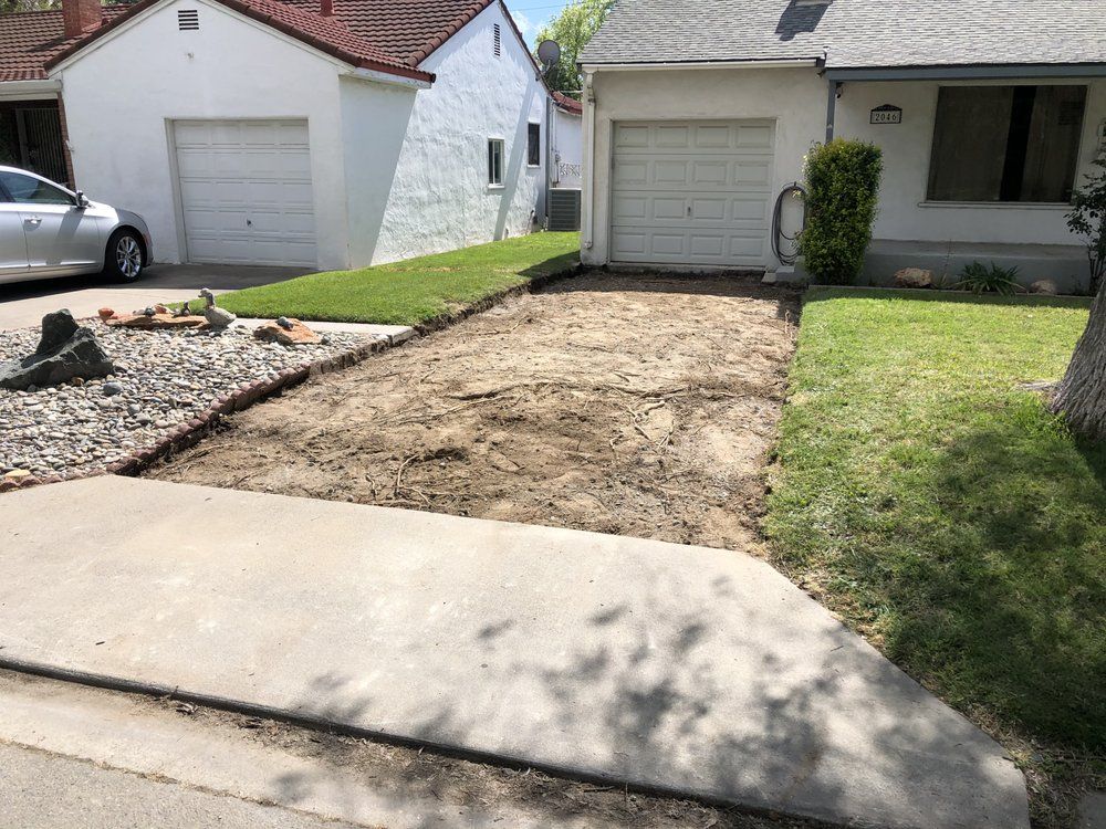 Front yard with a dirt patch between two houses, bordered by a sidewalk and lawn.