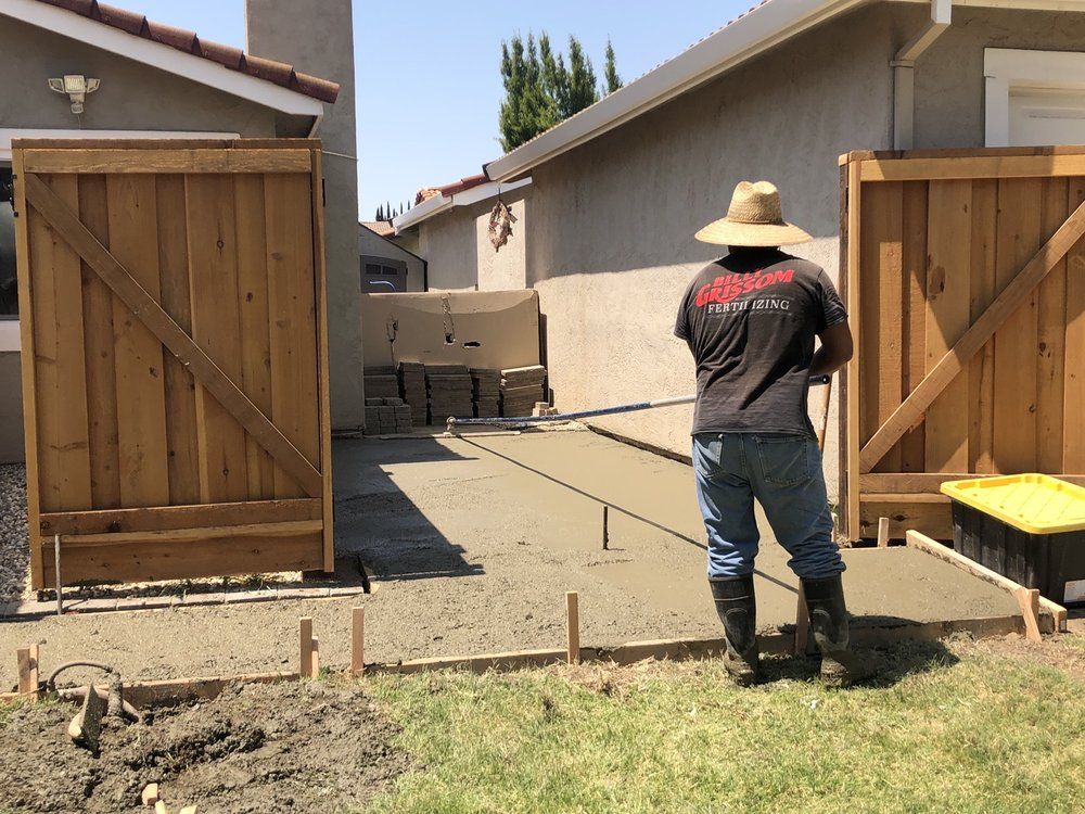 Backyard walkway between open wooden gates, with a person standing near a house and fence.