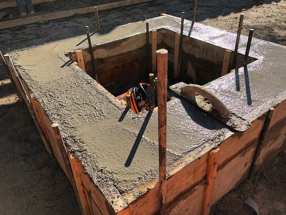 Concrete rooftop utility shaft under construction with rebar and tools inside a square opening