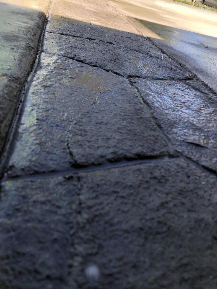 Close-up of wet, dark stone pavement with sunlight reflecting near the curb
