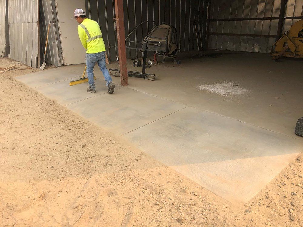 Worker in a neon safety vest stands on a concrete slab inside a construction site.