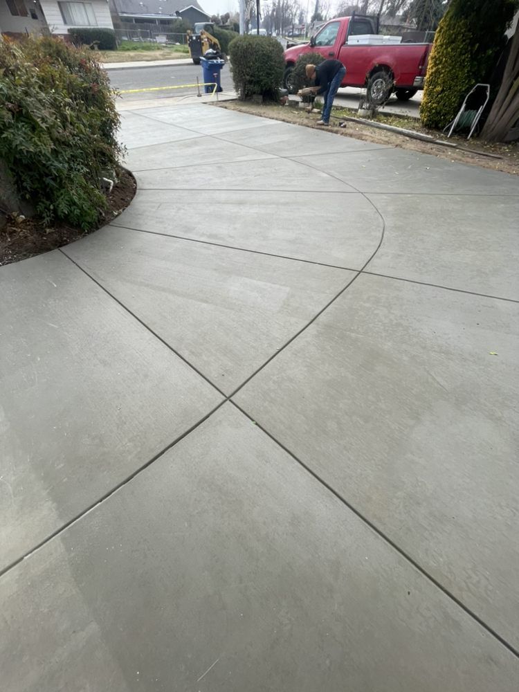 Curved concrete driveway and sidewalk with a person near parked red SUV in a residential neighborhood