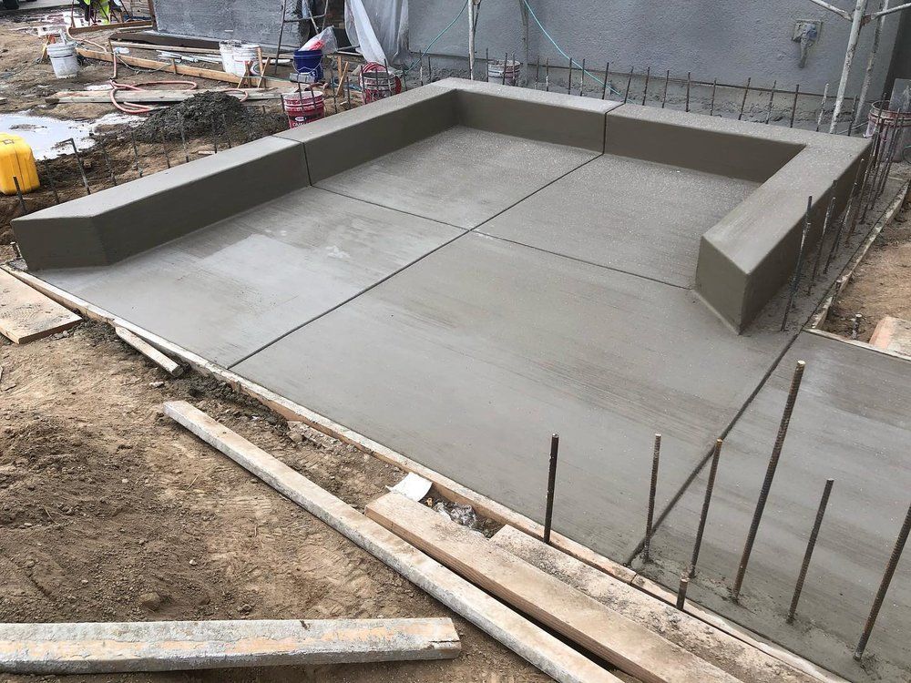 Freshly poured concrete slab with raised edges at a construction site