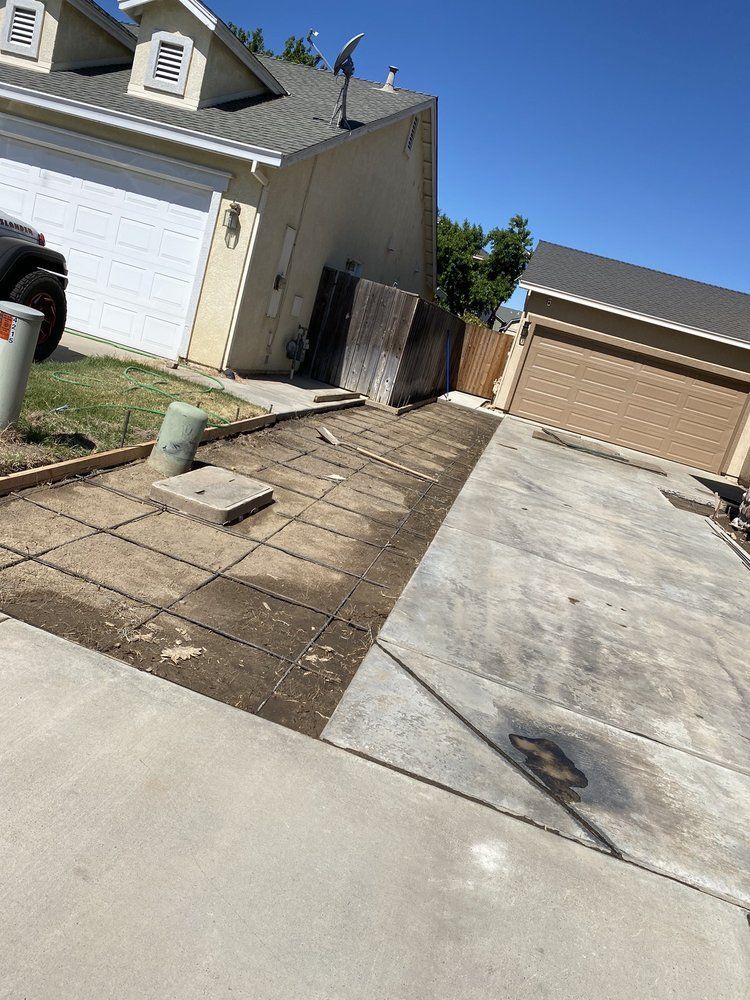 Driveway side yard with pavers, concrete slabs, and a detached garage on a sunny day
