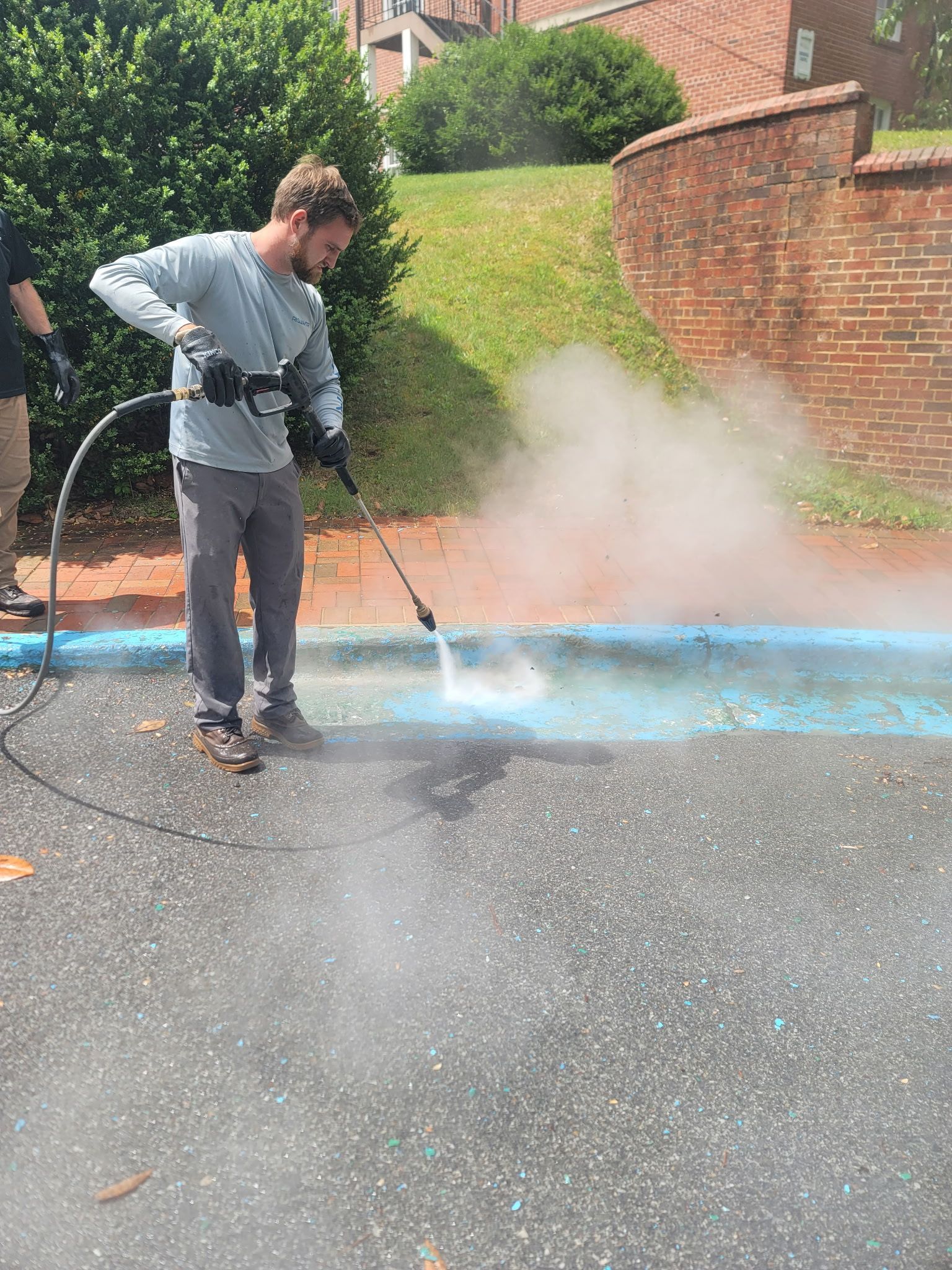 A person is using a high pressure washer to clean a sidewalk.