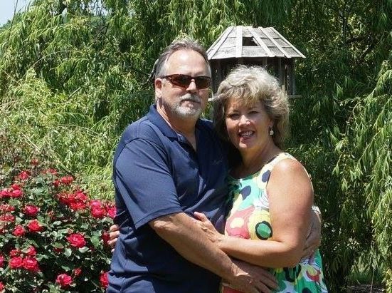 A man and a woman are posing for a picture in front of a birdhouse.
