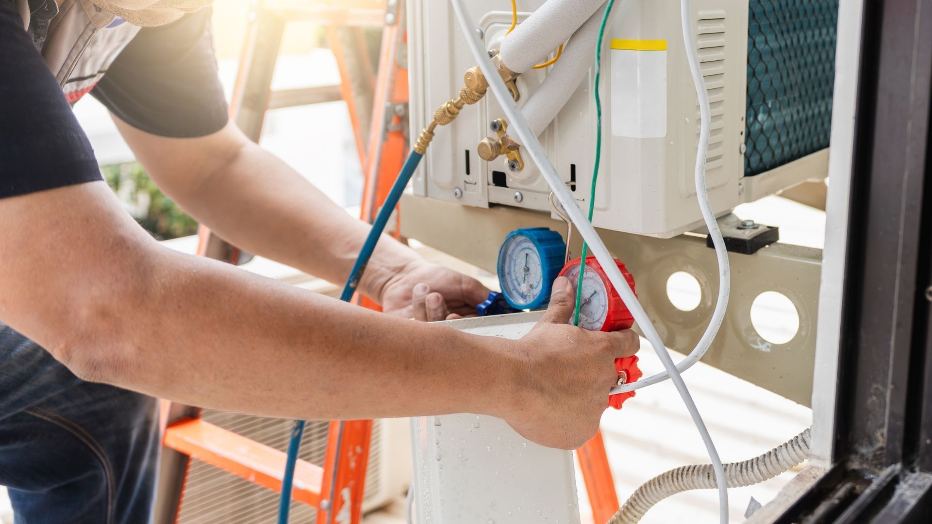 Technician adjusting gauges and tubing on HVAC equipment outdoors