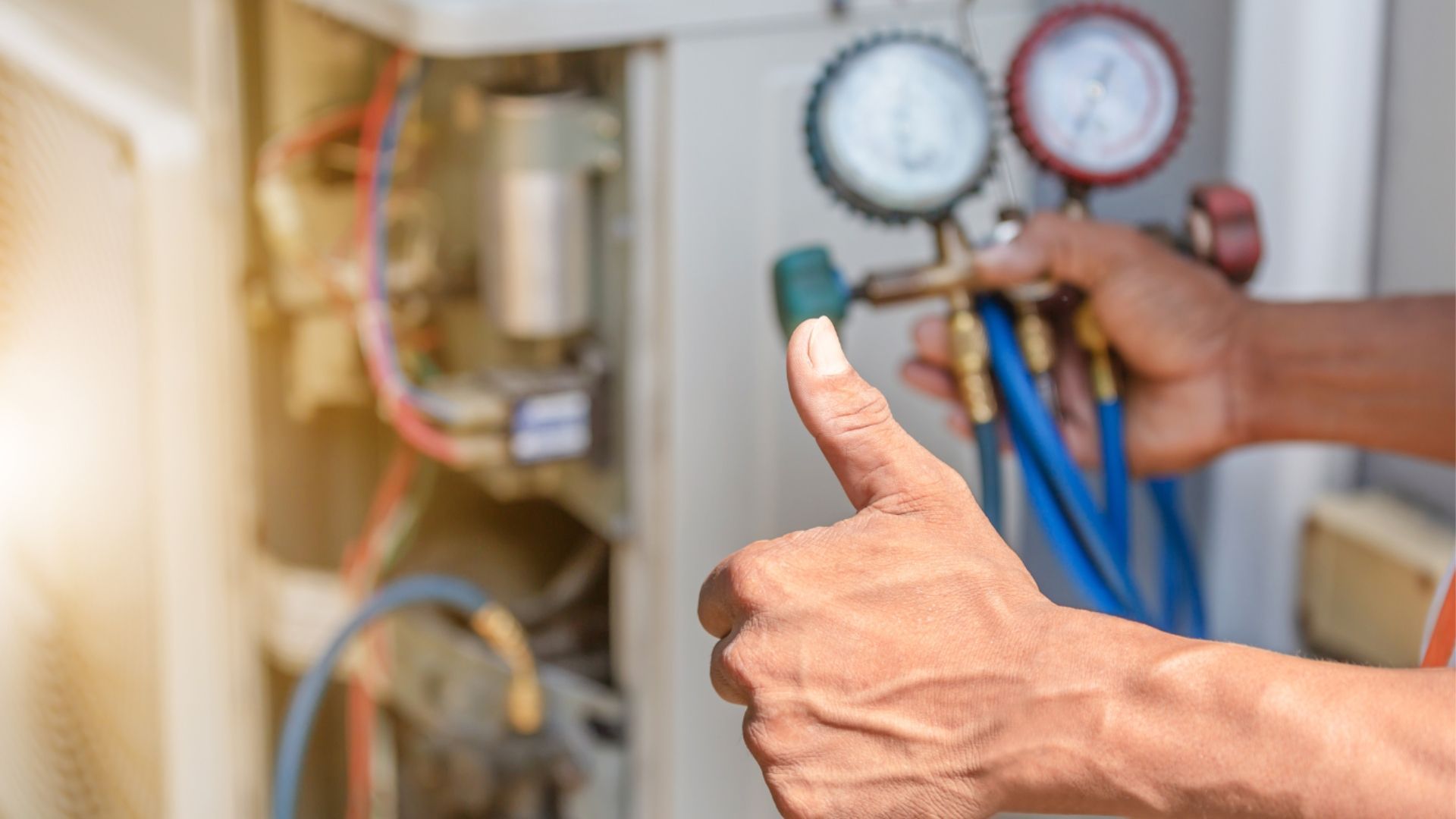 Hand giving thumbs-up beside HVAC gauges and blue hoses during a service check
