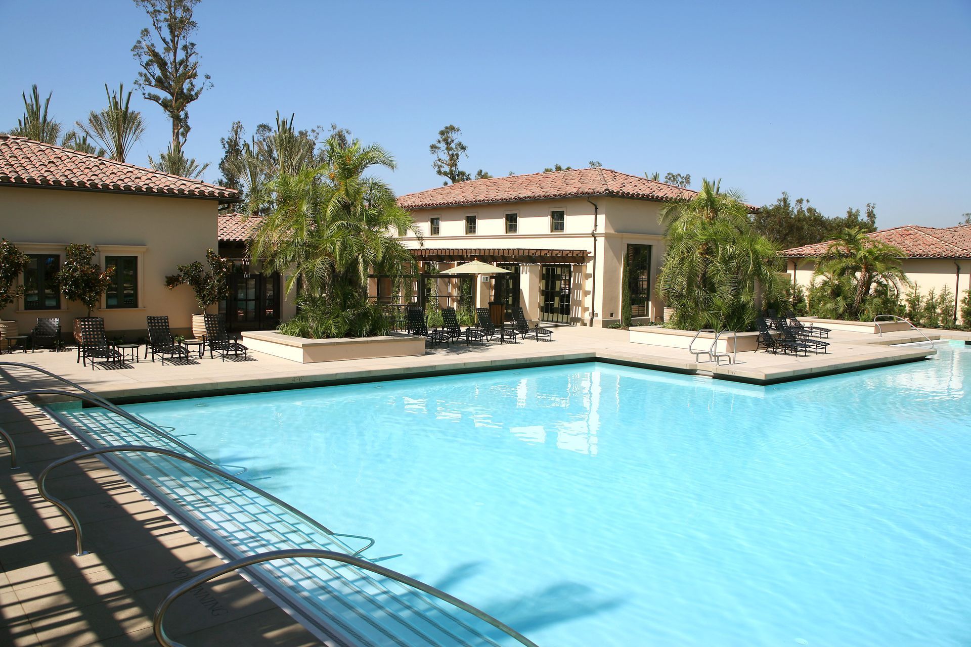 Pool with light blue water and beige building in the background, sunny day.