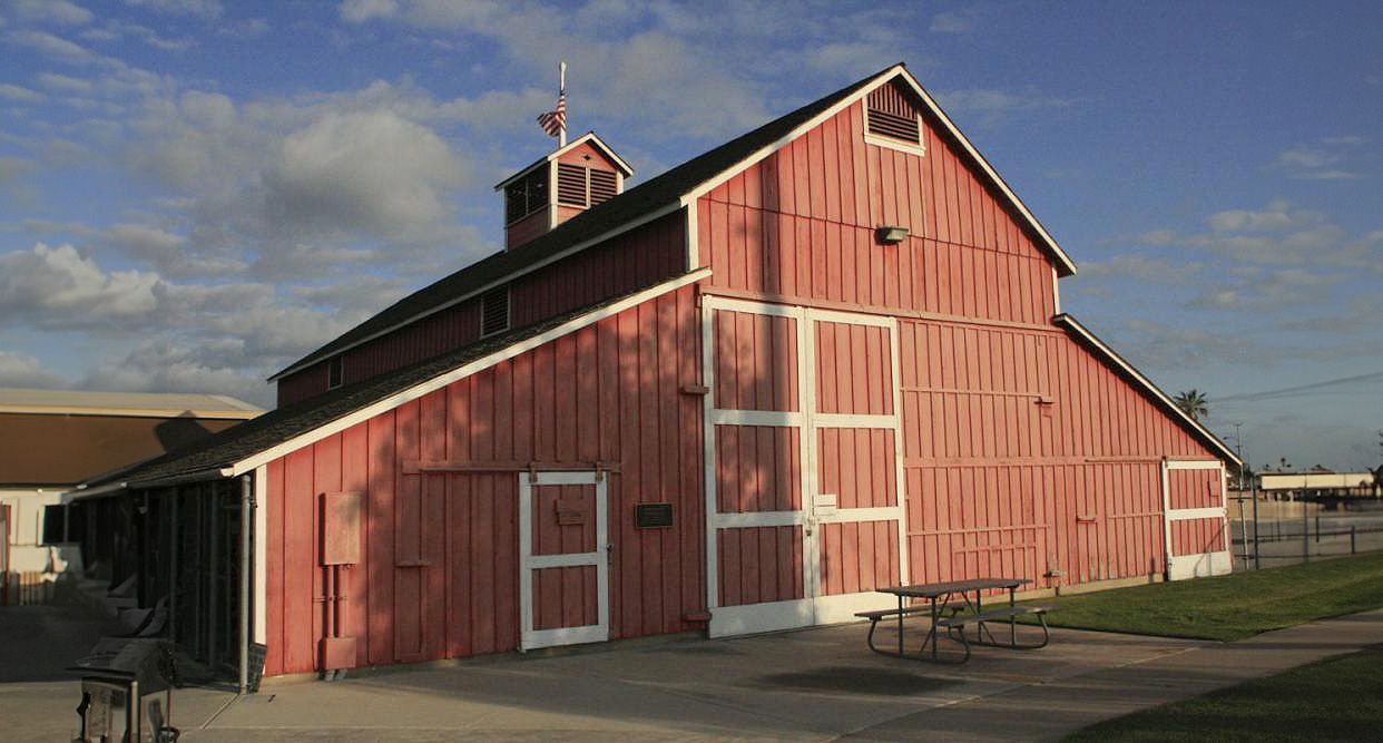 Red barn with white trim under blue sky.