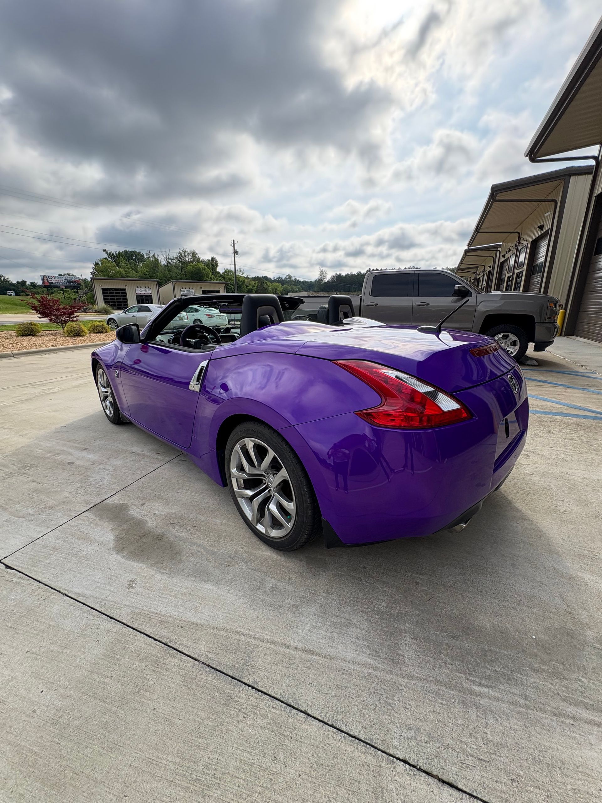 Purple convertible car parked outside under a cloudy sky.