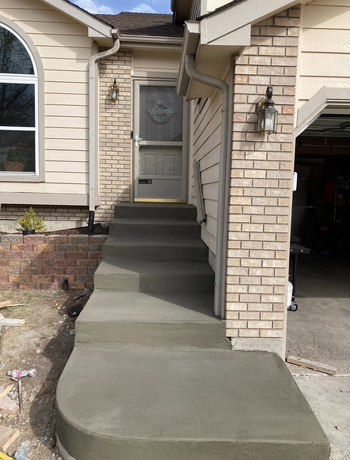 Front walkway and steps leading to a house entrance, with a concrete ramp beside the porch.