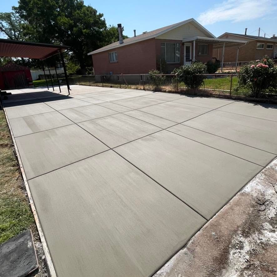 Freshly poured concrete driveway beside a brick house on a sunny day
