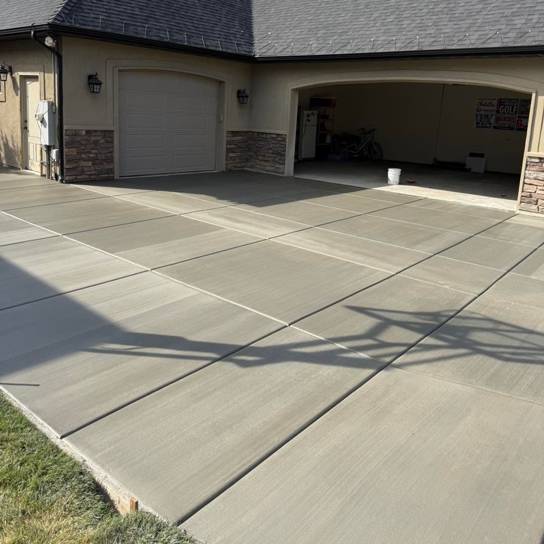 Two-car garage with a wide concrete driveway and stone-trimmed exterior in front of a house