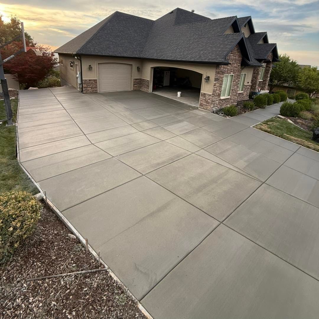 Suburban house with a large light-gray concrete driveway at sunset