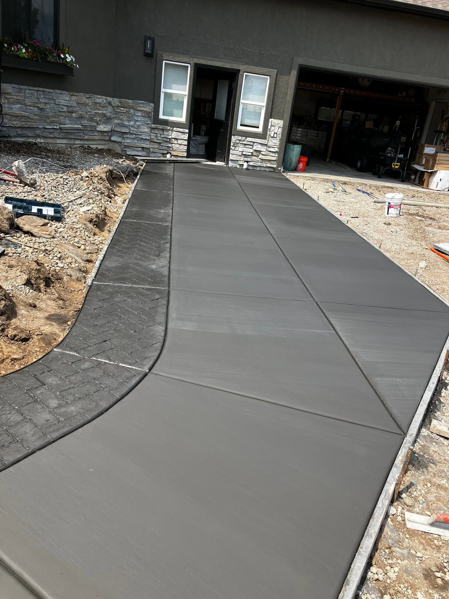 Fresh concrete walkway leading to a house entrance, with unfinished landscaping on both sides.