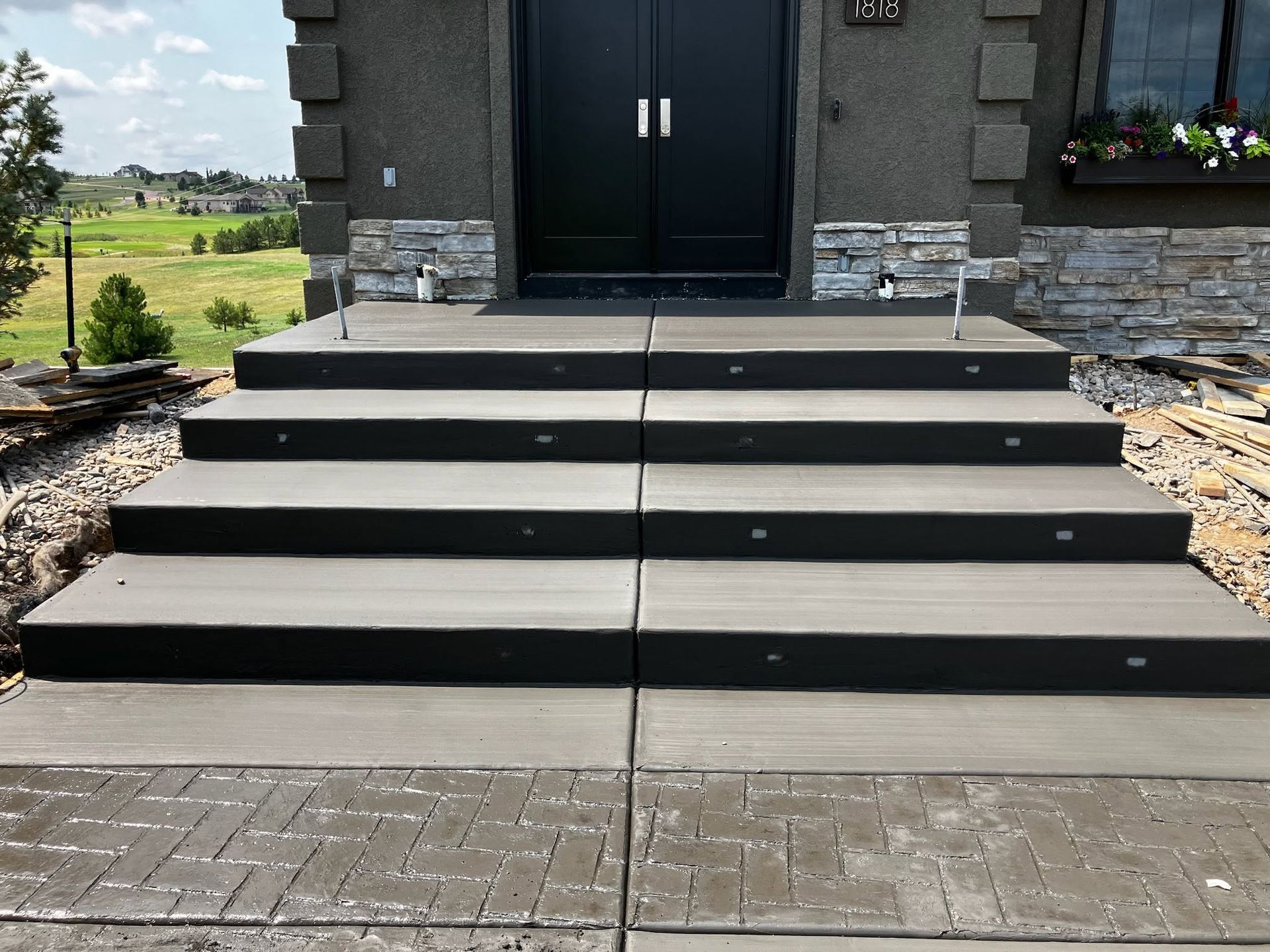 A concrete walkway leading to a house with a lush green lawn.