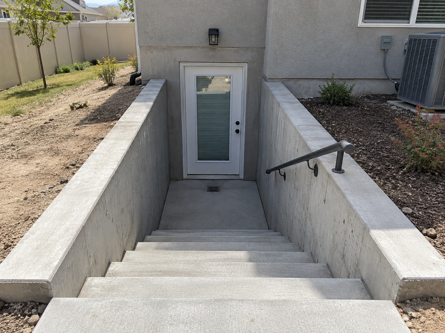Finished walkout basement entry with concrete steps and retaining walls at a Utah home